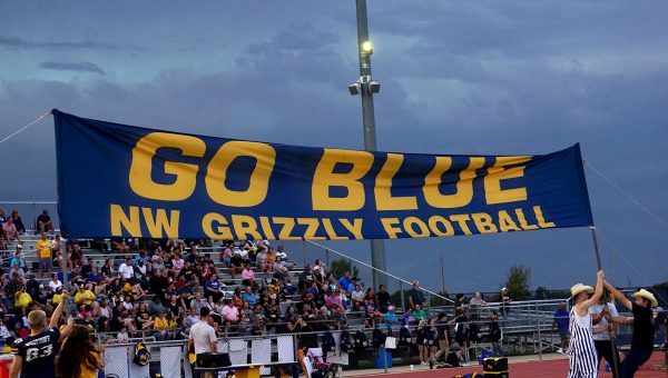 Students show off a banner at the Junction City game Friday night as storm clouds approach